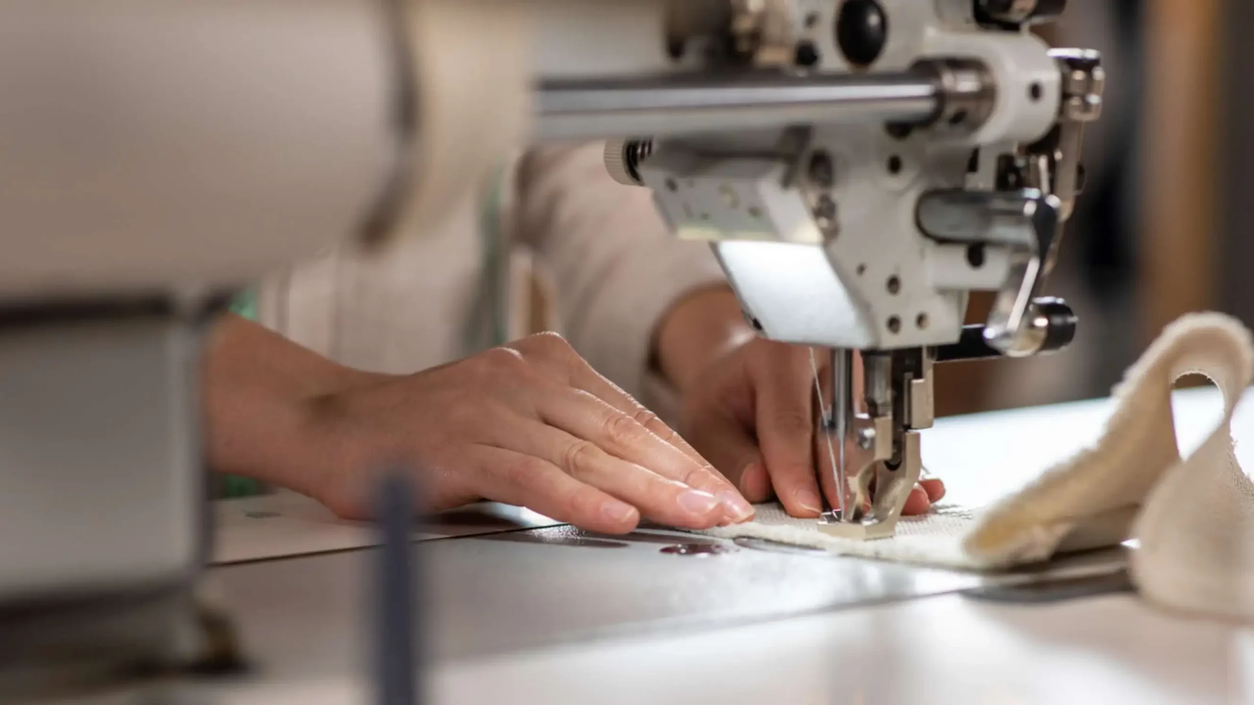 Tailor sewing fabric on industrial machine showing handcrafted bespoke tailoring process