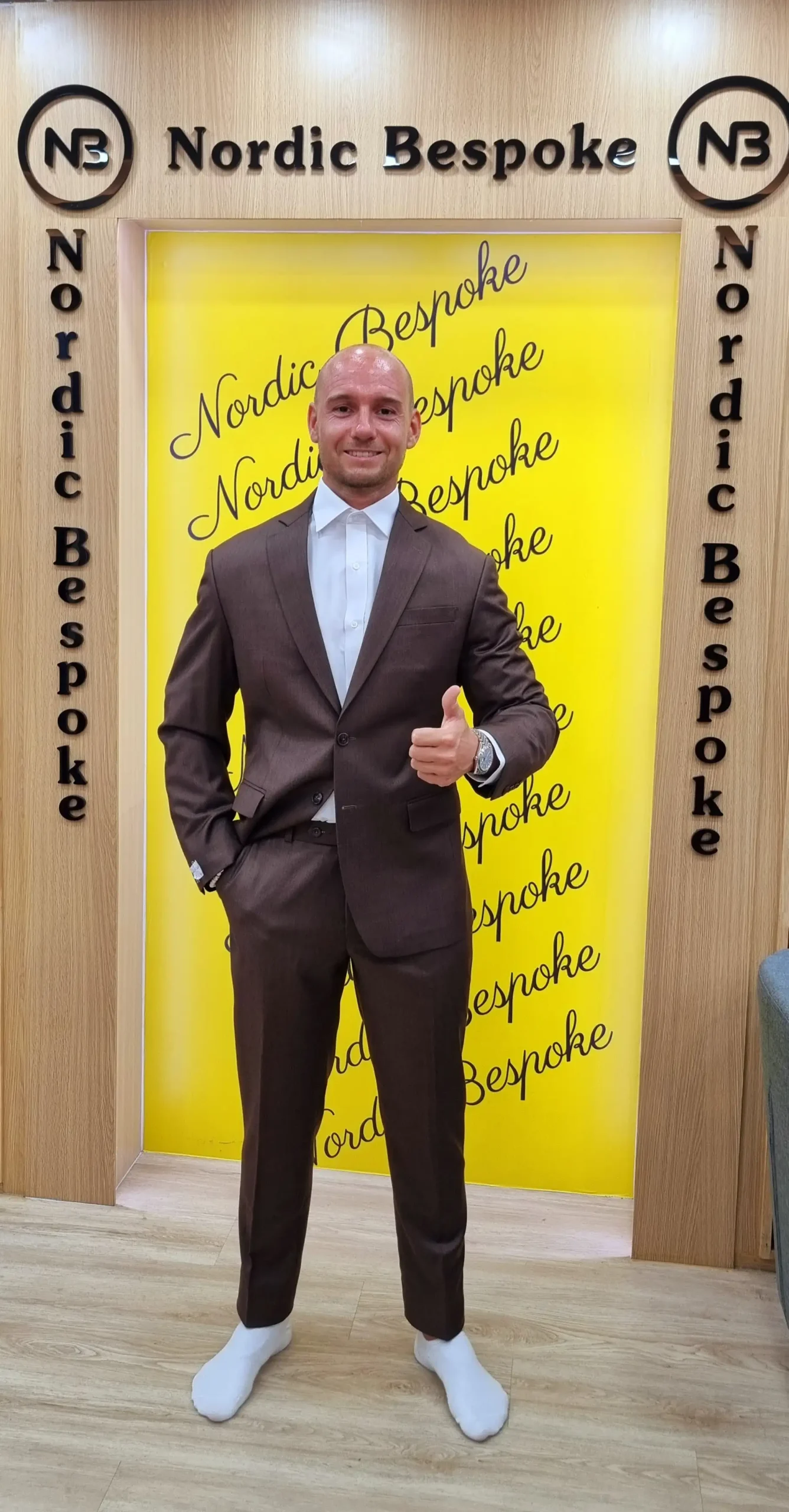 Customer wearing a brown three-piece suit with white trainers
