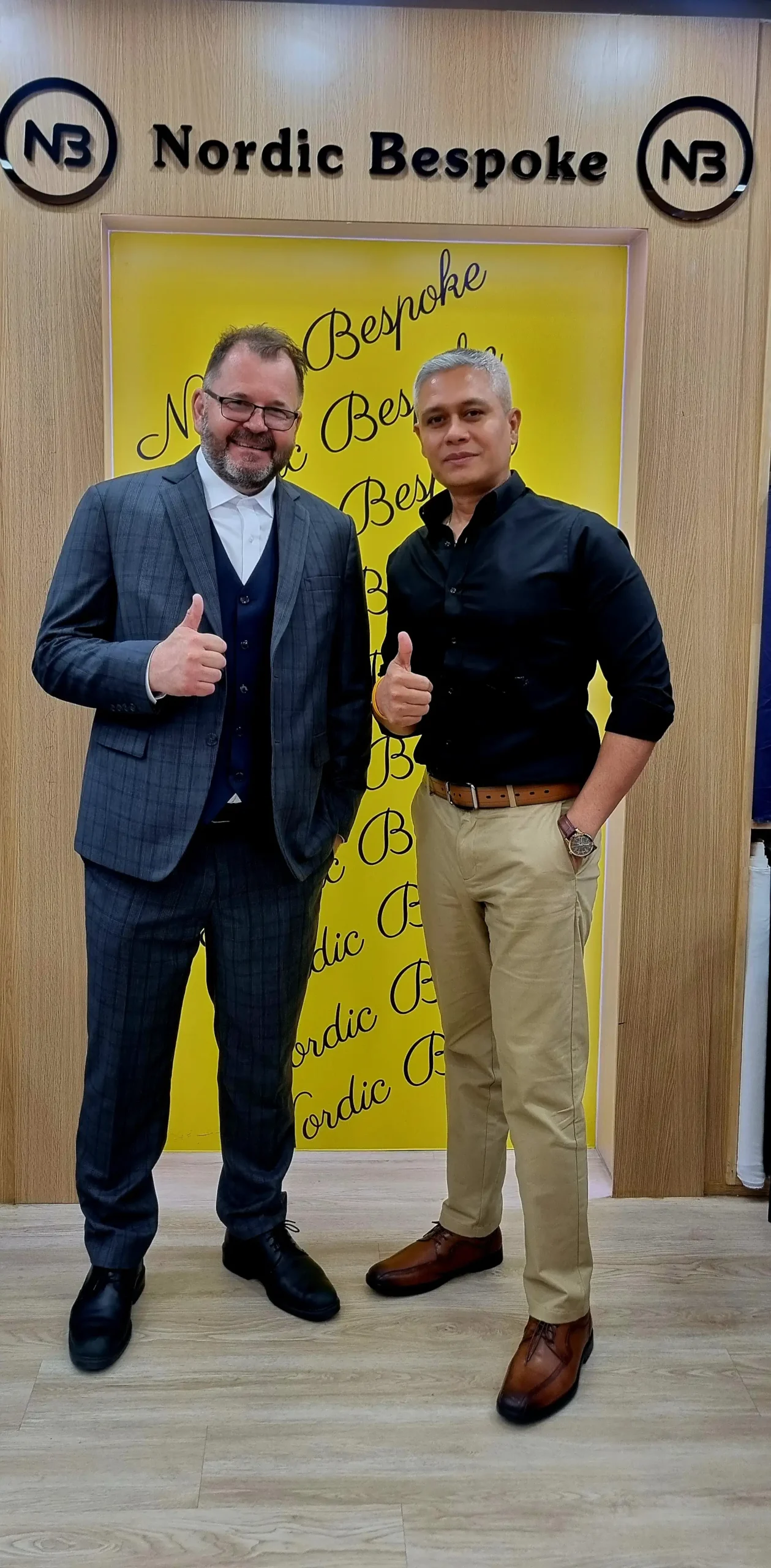 Two men posing in the showroom, one wearing a dark three-piece suit