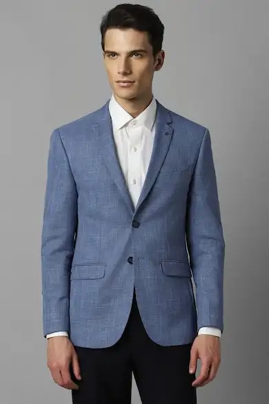 Man wearing a textured blue blazer with dark trousers