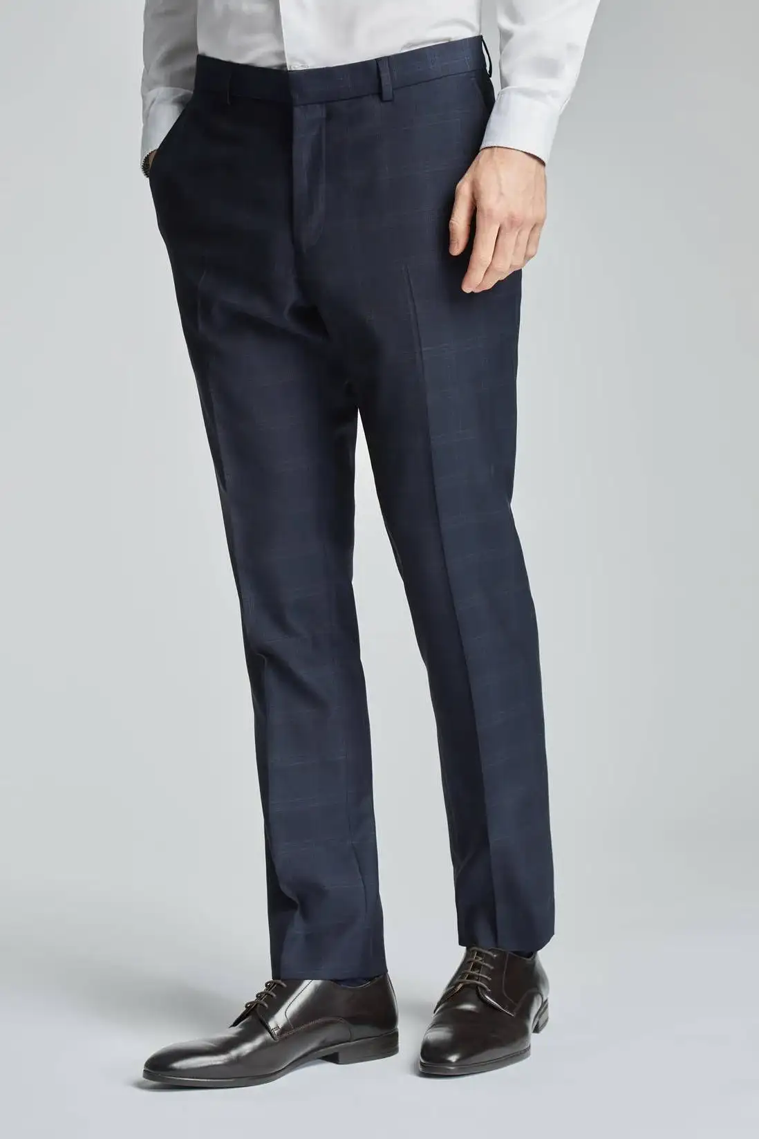 Dark trousers worn with a white shirt and dark shoes