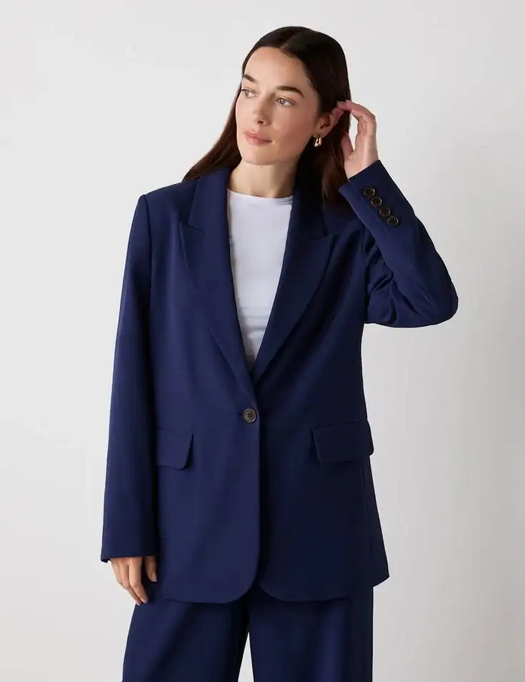 Woman wearing a navy blue oversized blazer with matching trousers and a white top, representing modern business casual style