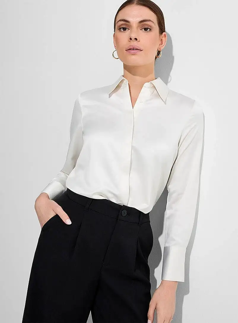 Female model wearing white satin long-sleeve blouse with pointed collar tucked into high-waisted black trousers – bespoke women's elegant blouse