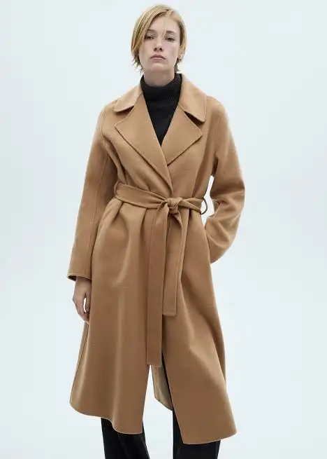 Woman wearing a belted camel-coloured overcoat with a black top