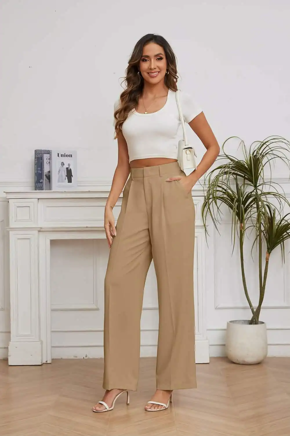 Woman wearing high-waisted tan trousers with a white cropped top