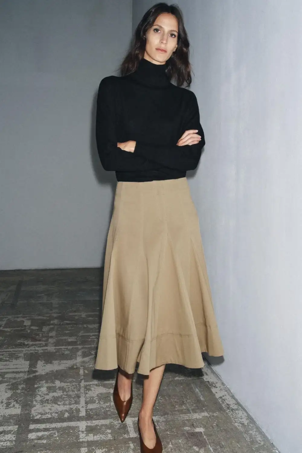 Female model wearing high-waisted beige A-line midi skirt paired with black turtleneck sweater and brown heels – bespoke women's skirt fashion