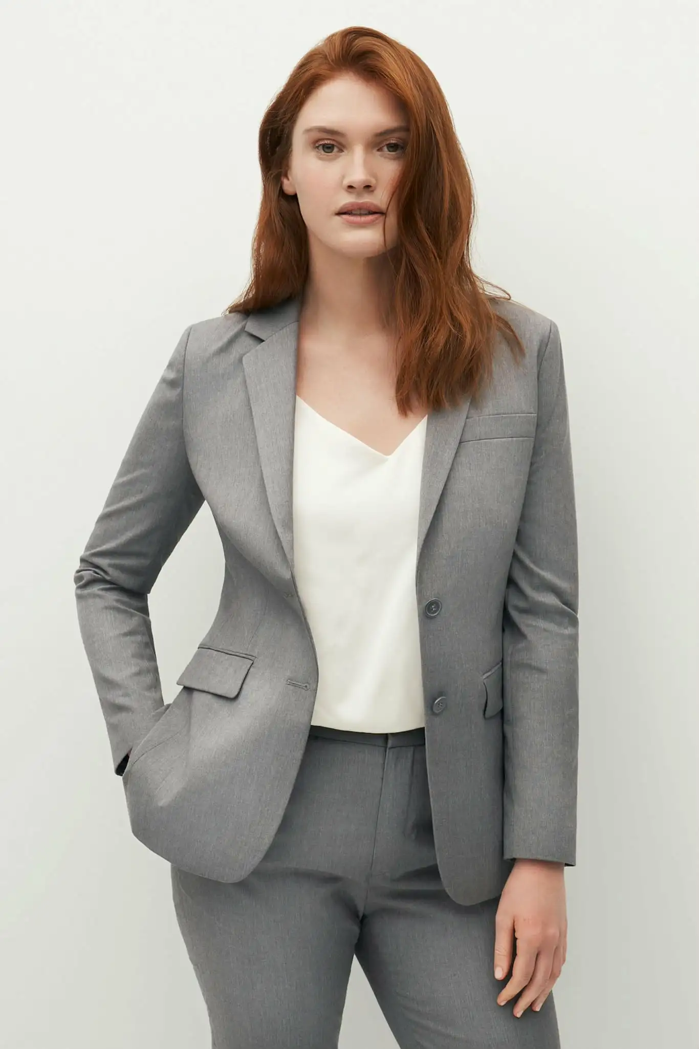 Woman wearing a grey trouser suit with a white top