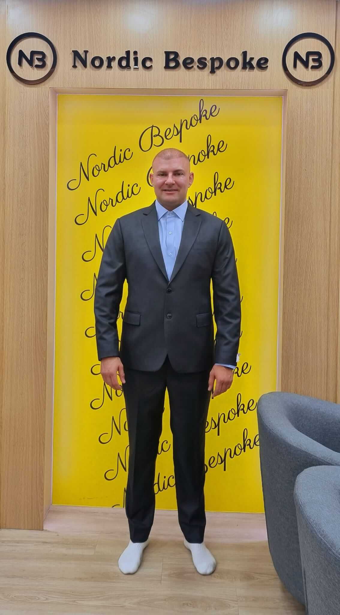 Customer wearing a dark suit with a white shirt and white trainers