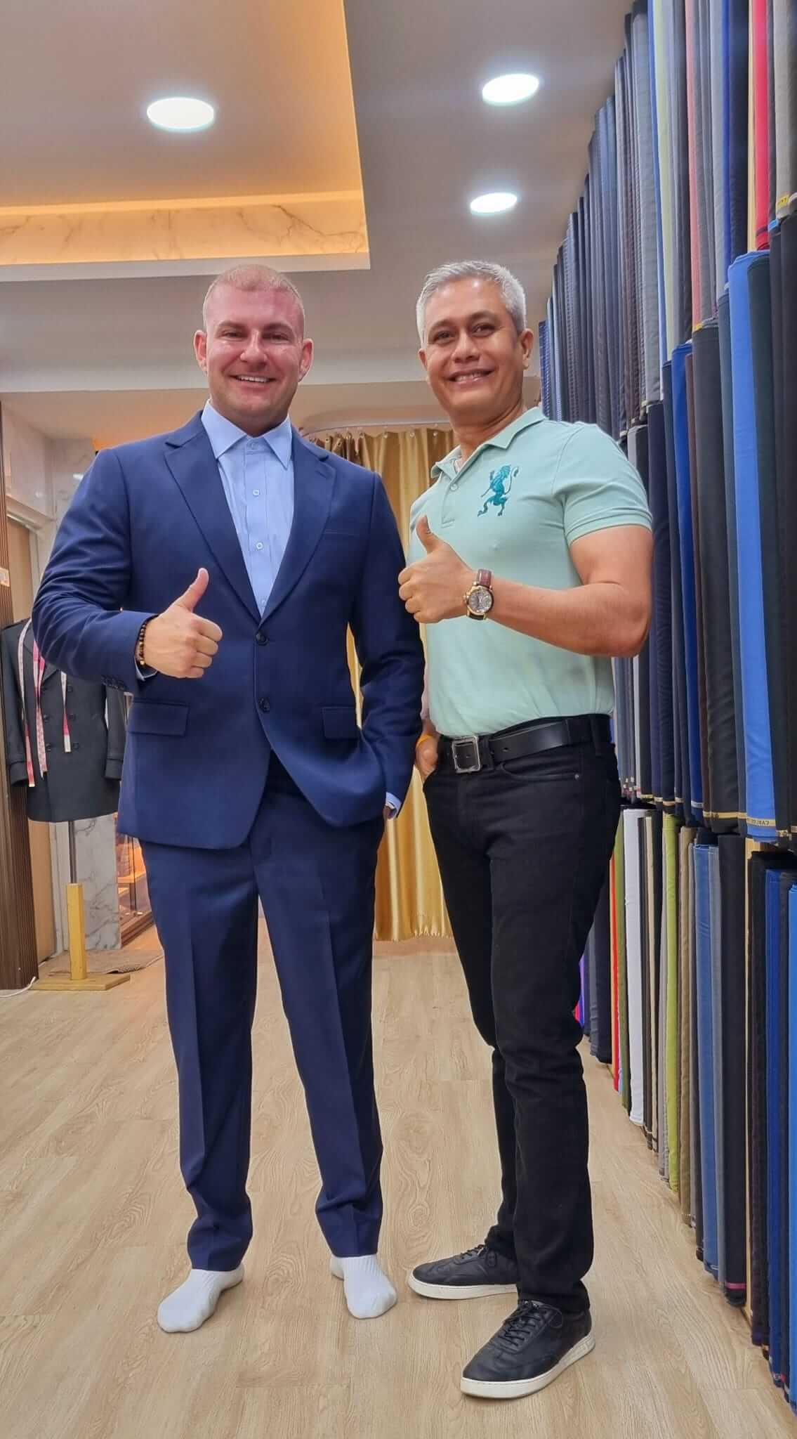 Two men posing in the showroom, one wearing a blue suit