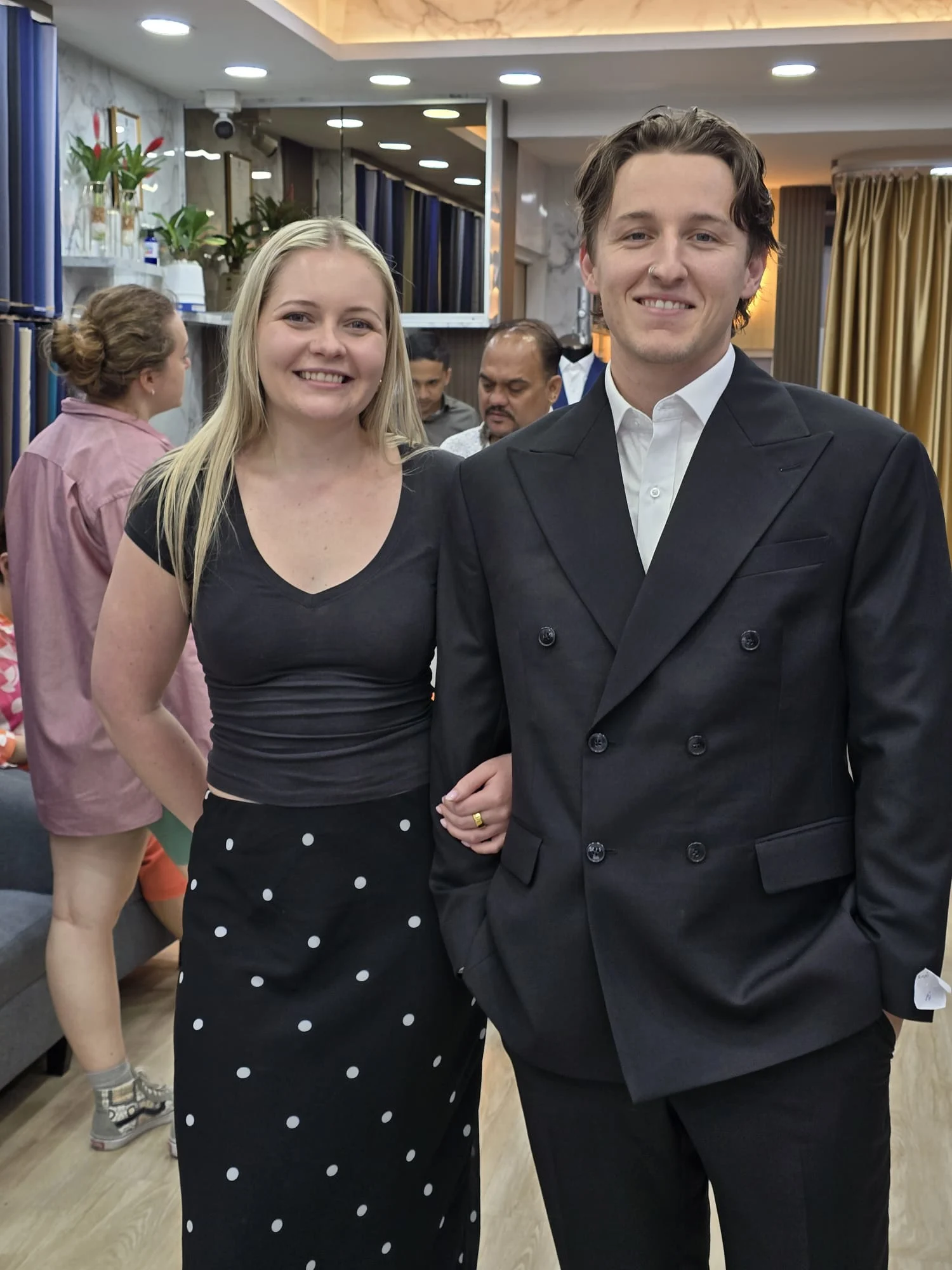 Two customers posing together in a dark suit and dark skirt outfit
