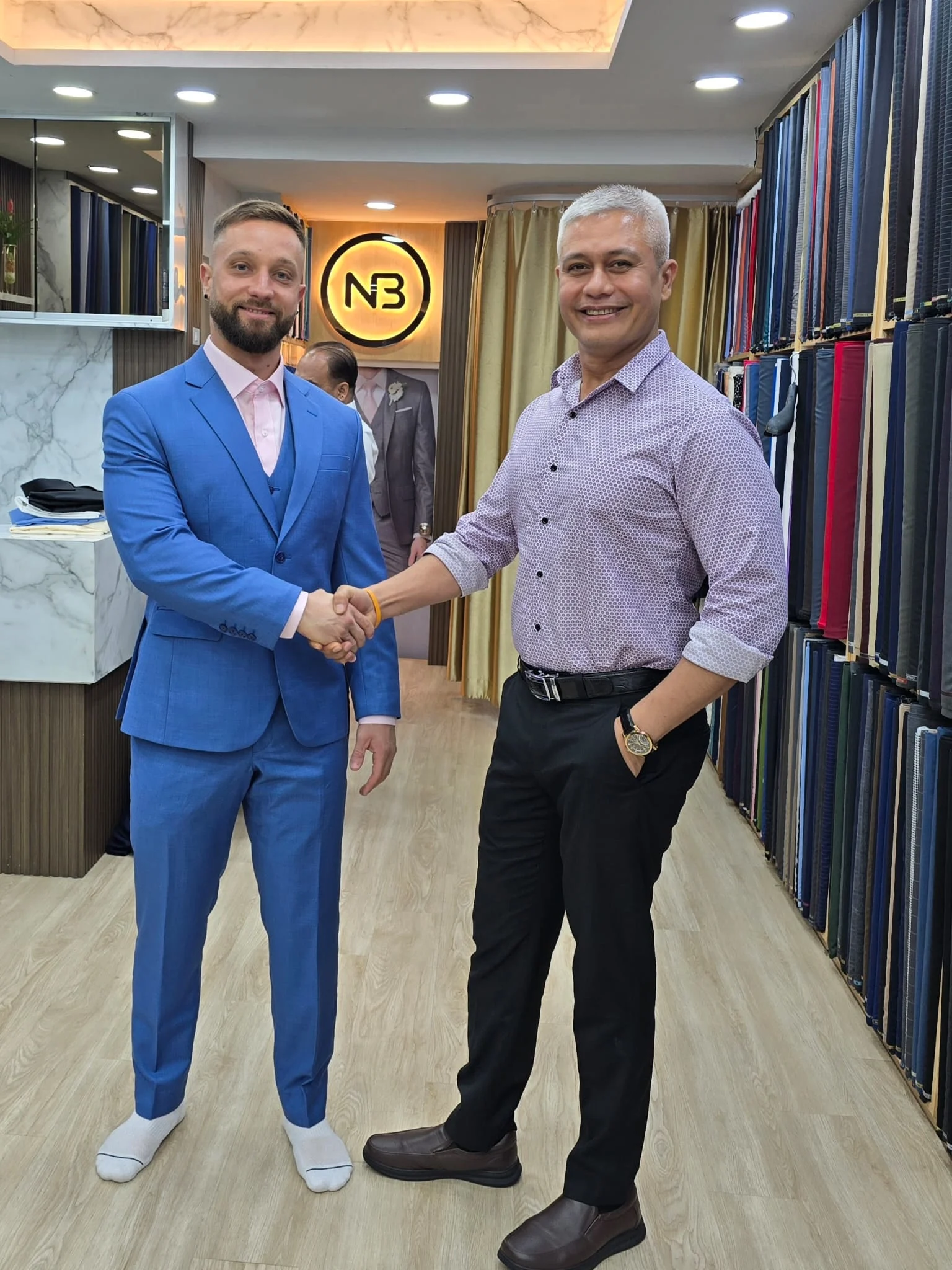 Two men shaking hands in the showroom, one wearing a blue suit