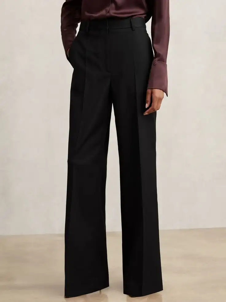 Female model wearing high-waisted black wide-leg trousers paired with silky maroon long-sleeve blouse – bespoke women's elegant pant ensemble