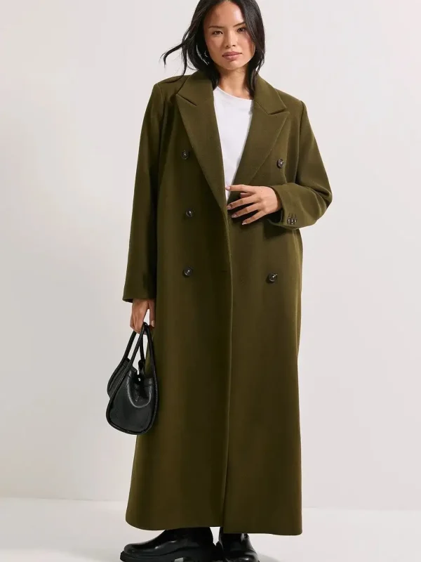 Woman wearing a long olive green double-breasted overcoat, carrying a black handbag, styled for sophisticated winter fashion